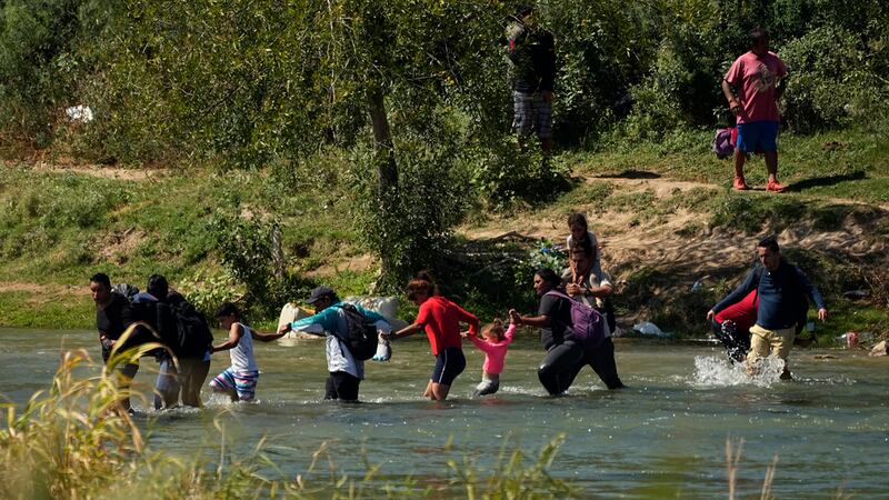 Migrantes cruzan de la mano el río Bravo desde México a Estados Unidos, el 21 de septiembre de...
